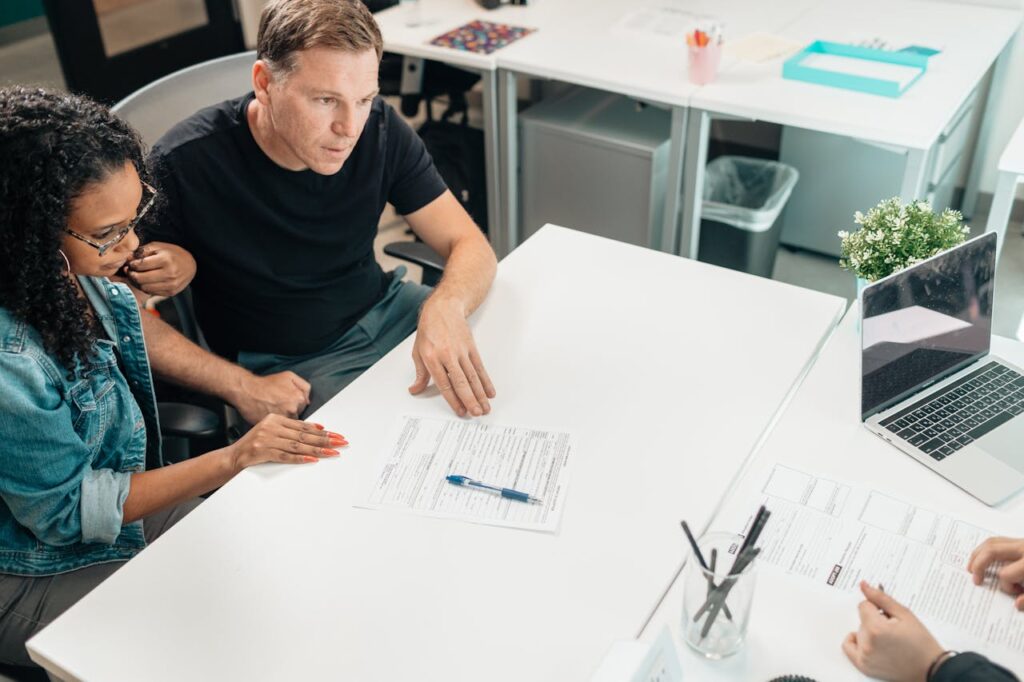 pexels-photo-7979404-5 A couple discusses legal documents with a professional in a modern office setting.