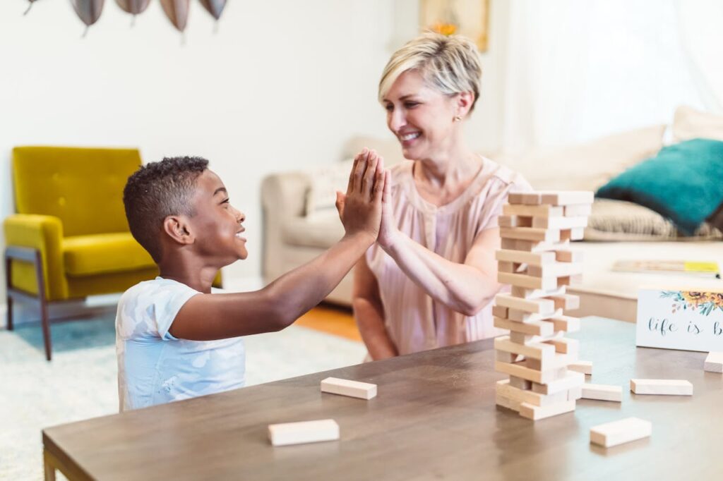 pexels-photo-8798892-5 A joyful mother and son playing Jenga and sharing a high five at home.
